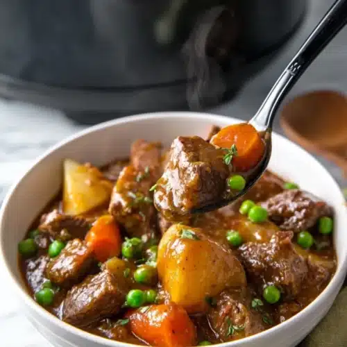 Crockpot beef stew with tender beef, carrots, potatoes, and peas in rich gravy