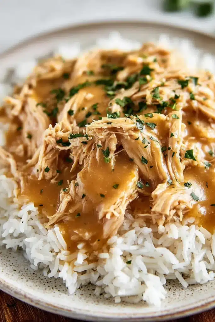 Crockpot chicken and gravy served over rice with creamy sauce