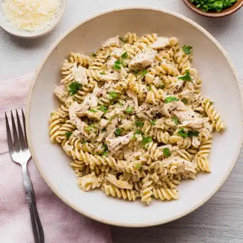 Crockpot garlic parmesan chicken pasta with rotini and parsley in a creamy sauce