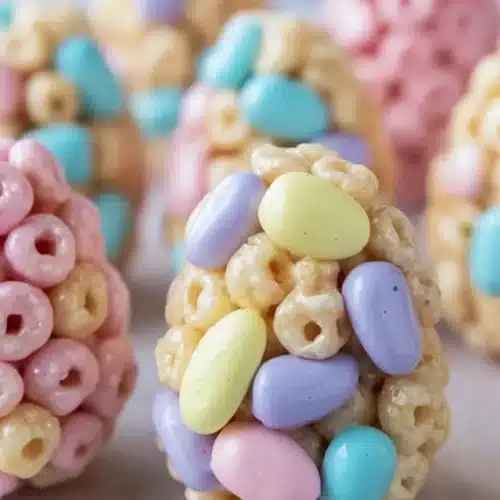Pastel Easter egg Rice Krispie treats coated in colorful candy shells on stone surface