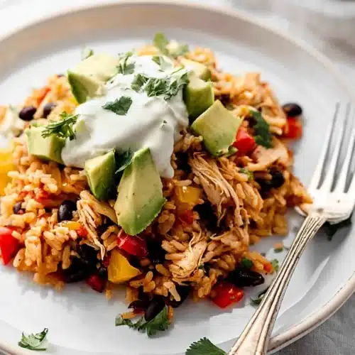 Easy Chicken Burrito Casserole 4 Easy chicken burrito casserole with avocado, black beans, and sour cream on ceramic plate
