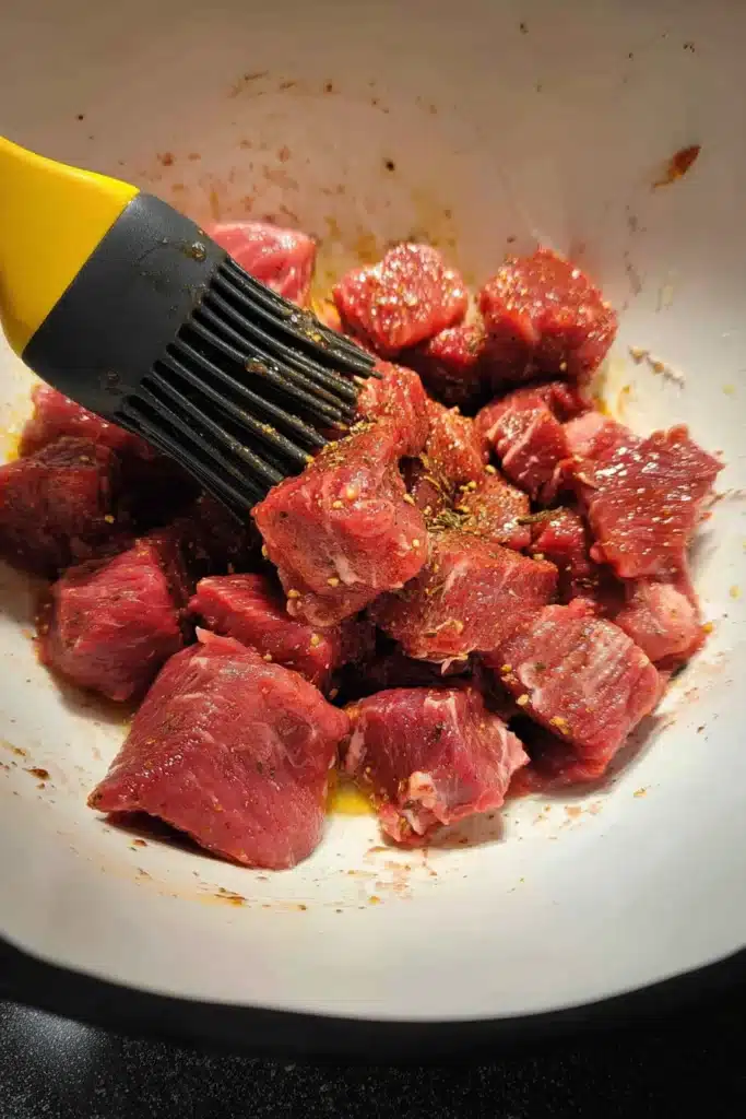 Garlic Butter Air Fryer Steak Bites raw steak cubes being seasoned in bowl