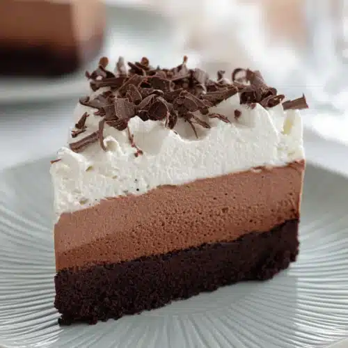 Gluten-free chocolate mousse cake slice with whipped cream and chocolate shavings