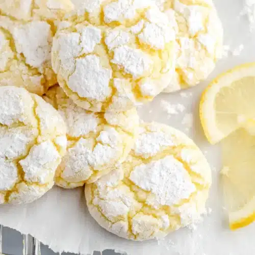 Soft lemon crinkle cookies with powdered sugar cracks and fresh lemon slices