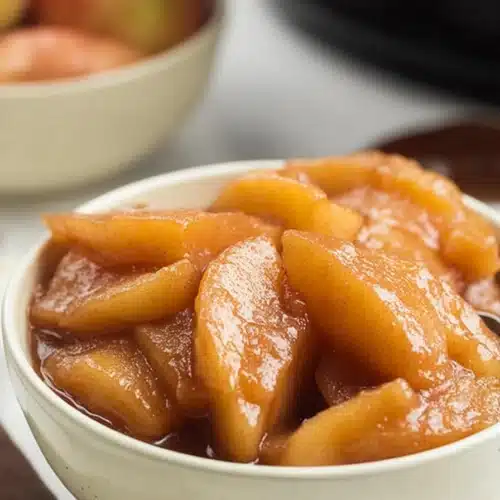 Slow Cooker Cracker Barrel Fried Apples cooking in a slow cooker with cinnamon sauce
