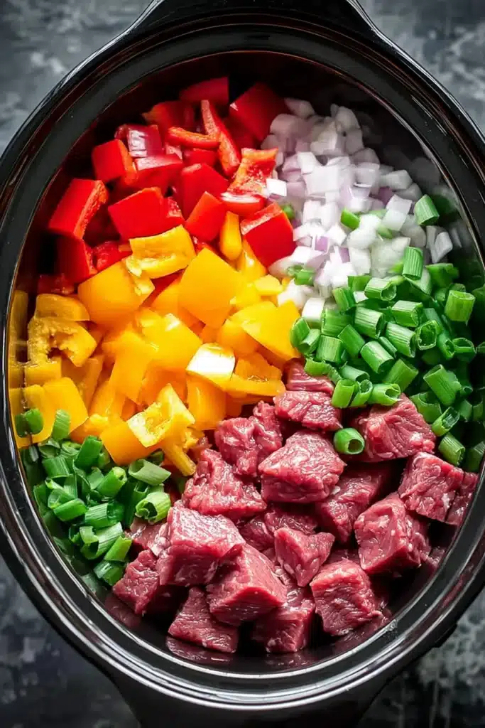 Slow Cooker Pepper Steak Recipe That’s Easy and Flavorful 2 Slow Cooker Pepper Steak ingredients with raw beef and bell peppers in crockpot