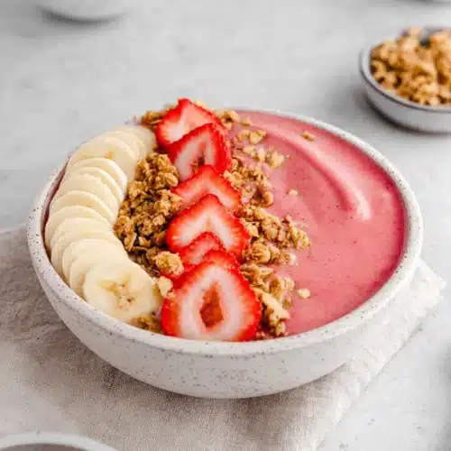 Strawberry banana smoothie bowl with granola, fresh fruit, and creamy texture