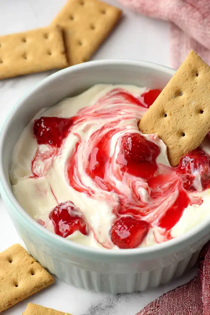 Strawberry Cheesecake Dip 1 Strawberry cheesecake dip with graham crackers and glossy fruit swirl