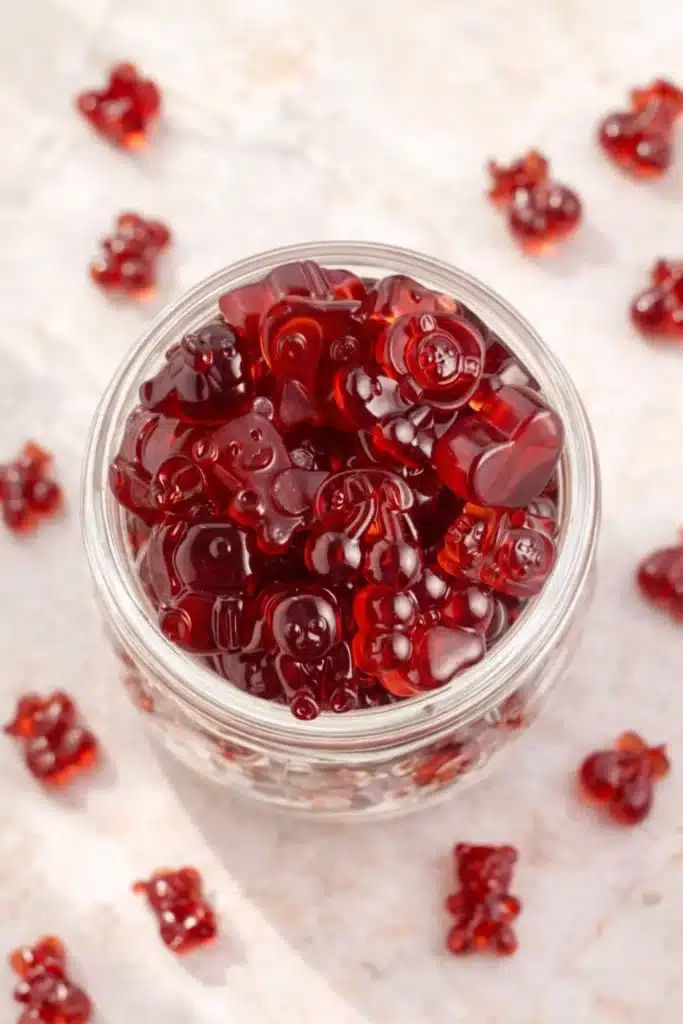 Top view of homemade Tart Cherry Gummies in glass jar on light surface