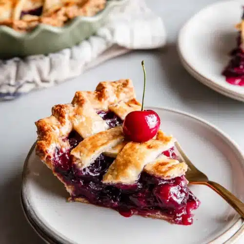 Slice of The best Cherry Pie homemade with glossy filling on ceramic plate