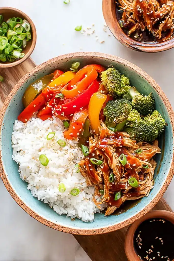 Teriyaki chicken rice bowl with broccoli, bell peppers, sesame seeds, and steamed white rice