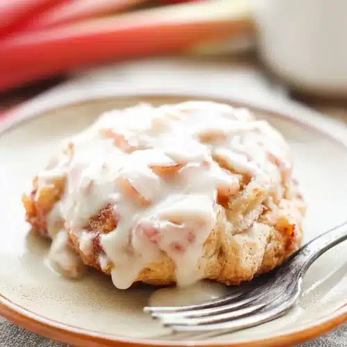 Baked Rhubarb Fritters Recipe You’ll Love 3 Baked rhubarb fritter with creamy glaze on white plate