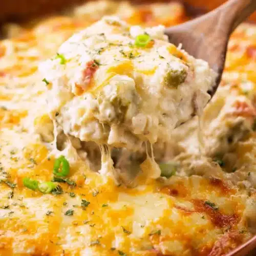 Chinese buffet crab casserole with melted cheese and green onions on a spoon