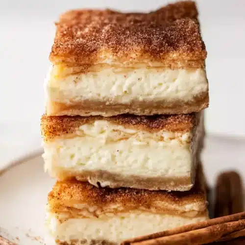 Churro cheesecake bars stacked with creamy layers and cinnamon sugar topping
