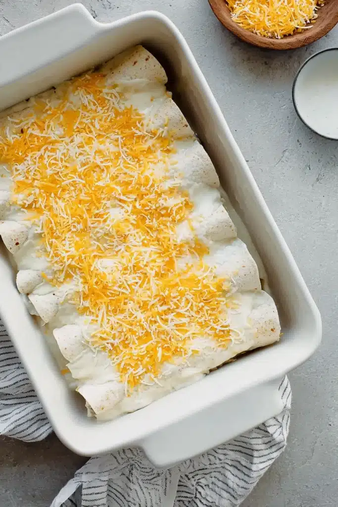 Sour Cream Chicken Enchiladas 2 Sour Cream Chicken Enchiladas in baking dish with creamy sauce and cheese
