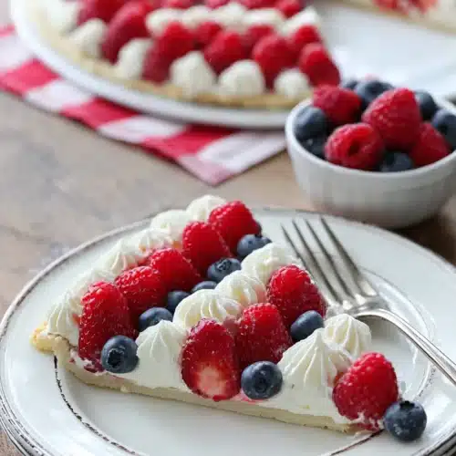 Easy American Flag Fruit Pizza slice with berries and cream on a white plate