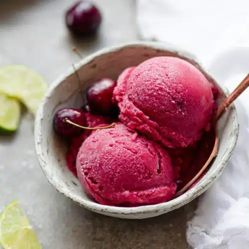 Fresh Cherry Sorbet 3 Fresh cherry sorbet scoops in a bowl with lime slice and spoon