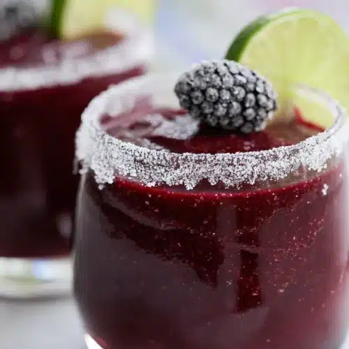 This frozen blackberry margarita features a rich, icy texture with fresh lime and a salted rim, creating a vibrant and refreshing cocktail perfect for summer gatherings.