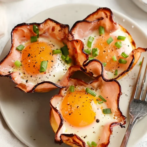 Ham and cheese egg cups with runny yolks and green onions on a plate
