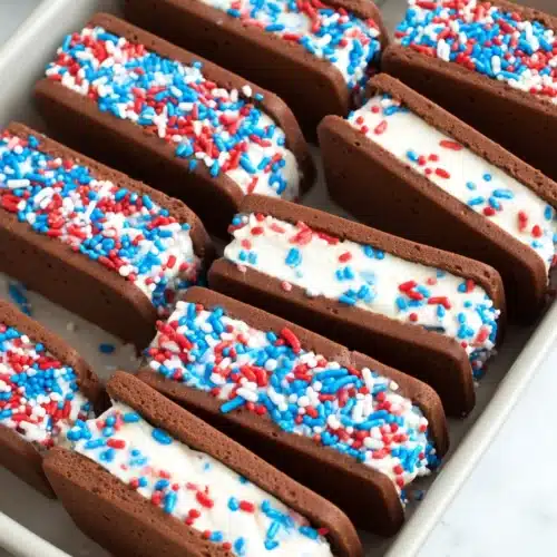 Patriotic mini ice cream sandwiches with red white and blue sprinkles in a tray