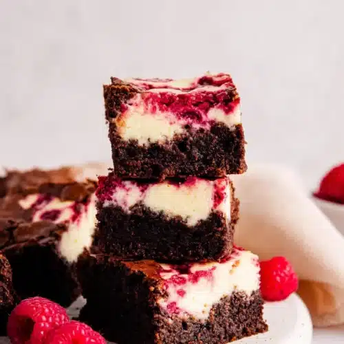 Raspberry Cheesecake Brownies 3 Stacked raspberry cheesecake brownies with creamy layers and raspberry swirl