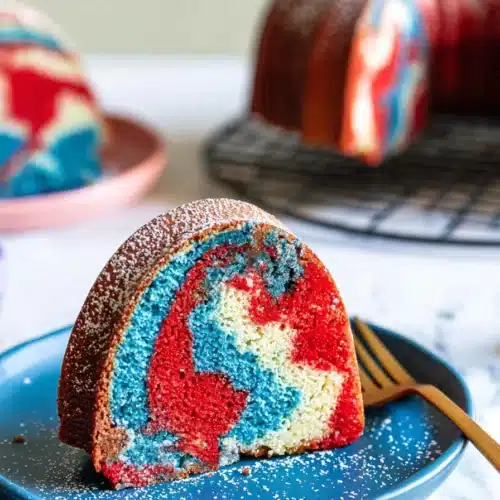 Red White And Blue Marble Cake slice with powdered sugar on blue plate