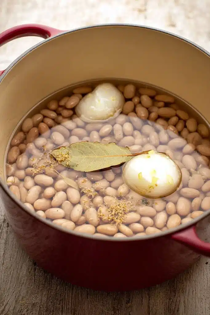 Refried beans soaking pinto beans with onion garlic and bay leaf