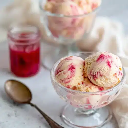 Creamy rhubarb ice cream with pink swirls served in bowls with rhubarb sauce