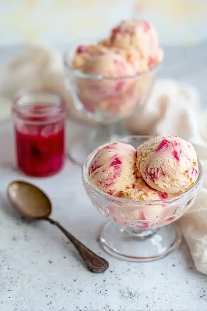 Creamy rhubarb ice cream with pink swirls served in bowls with rhubarb sauce