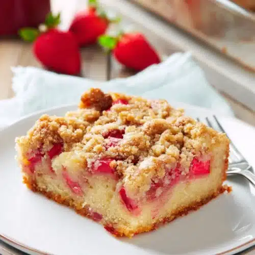 Rhubarb streusel cake slice with crumb topping on white plate