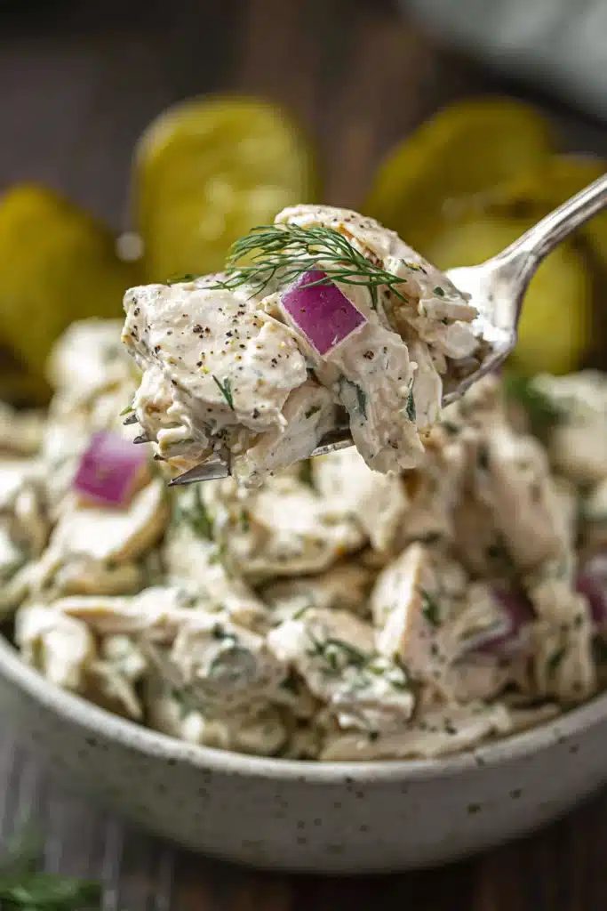 creamy dill pickle chicken salad with shredded chicken and red onions on spoon