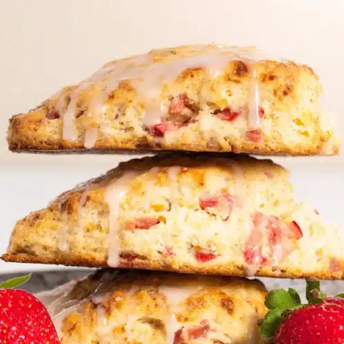 Strawberry rhubarb scones stacked with glaze and fresh strawberries
