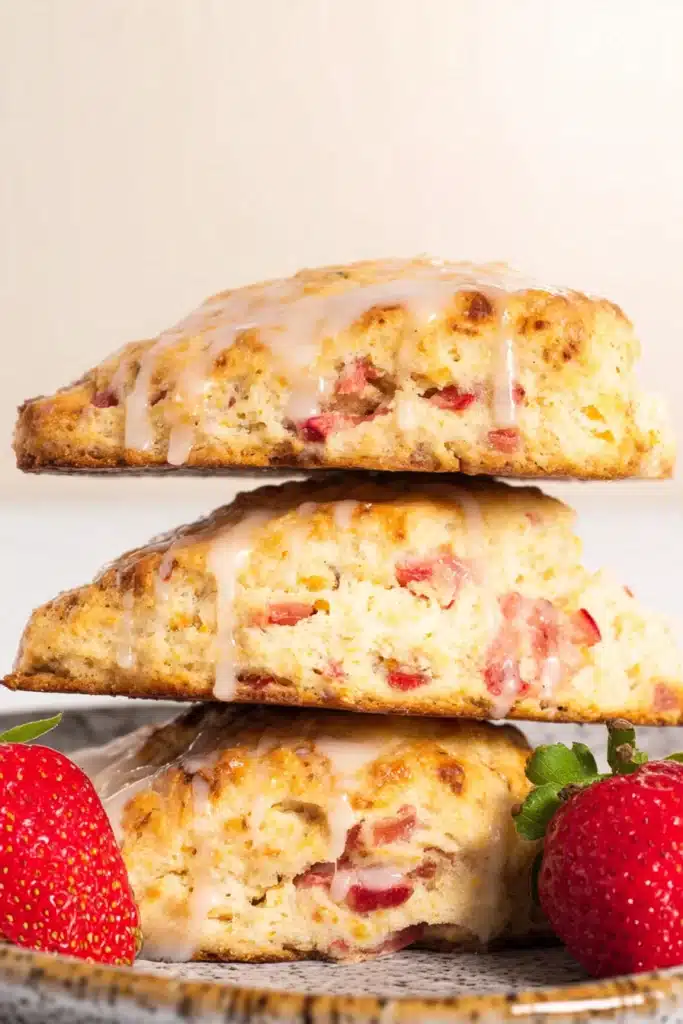 Strawberry rhubarb scones stacked with glaze and fresh strawberries