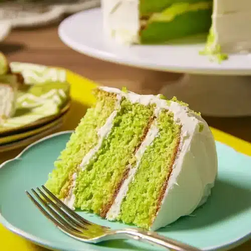 Moist lime cake slice with creamy frosting on plate