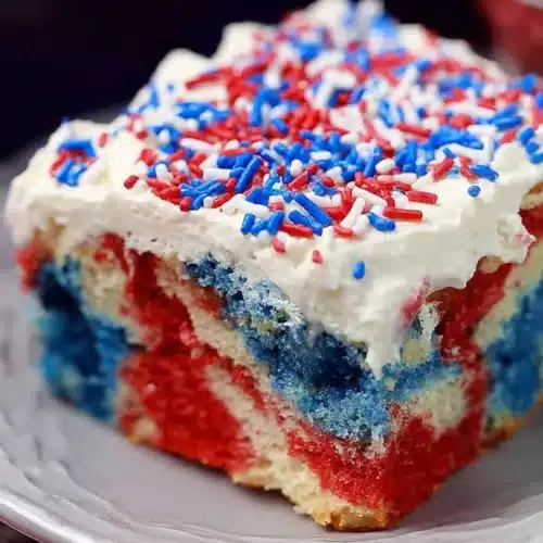 Patriotic Poke Cake slice with red white and blue layers and whipped topping