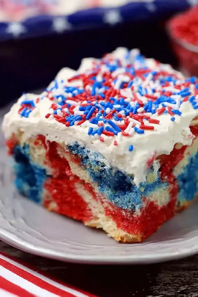 Patriotic Poke Cake slice with red white and blue layers and whipped topping