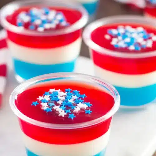 Red White & Blue Jello Shots layered dessert cups with sprinkles on platter