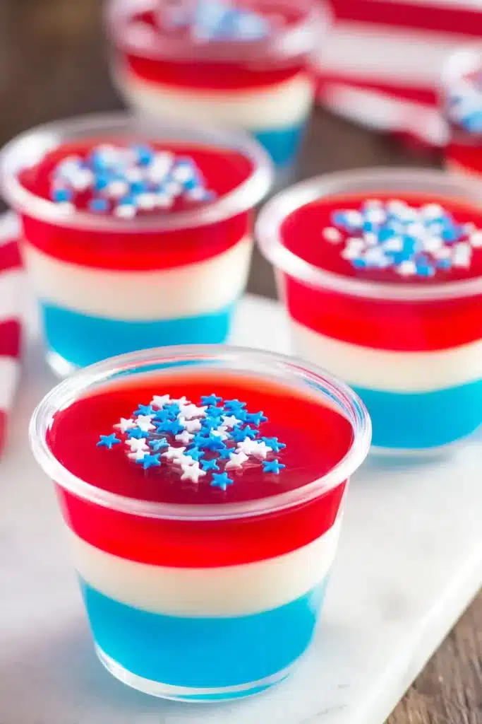 Red White & Blue Jello Shots layered dessert cups with sprinkles on platter