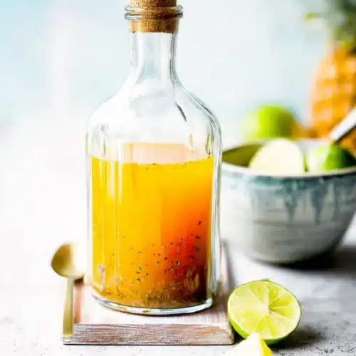 Apple cider vinegar drink with pineapple and lime in a glass bottle