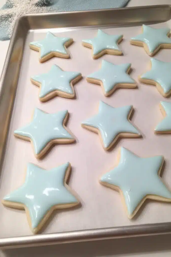 Star Cookies with blue royal icing and patriotic sprinkle borders on a rustic wood surface