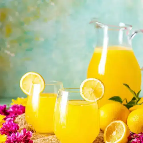 Fresh Mango Lemonade served in glasses with lemon slices and summer flowers