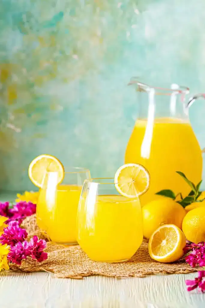 Fresh Mango Lemonade served in glasses with lemon slices and summer flowers