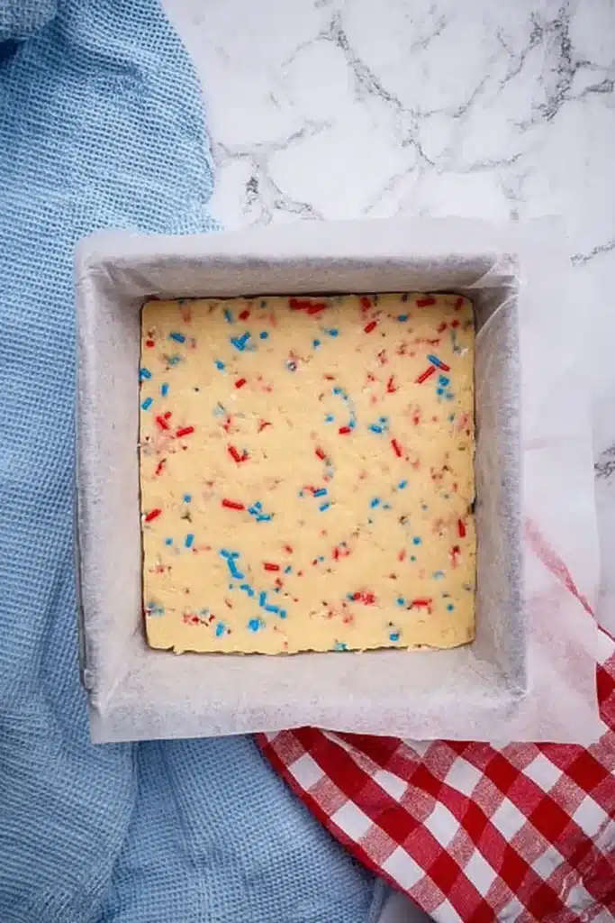 Patriotic Sugar Cookie Bars for the Perfect 4th of July Dessert 3 Patriotic sugar cookie bars dough pressed into baking pan with sprinkles