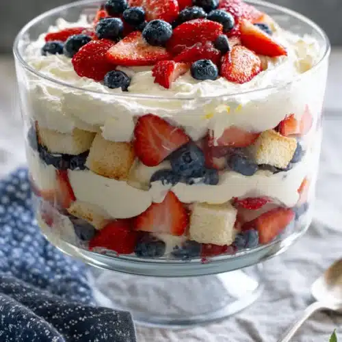 Patriotic trifle dessert with strawberries blueberries whipped cream and cake layers