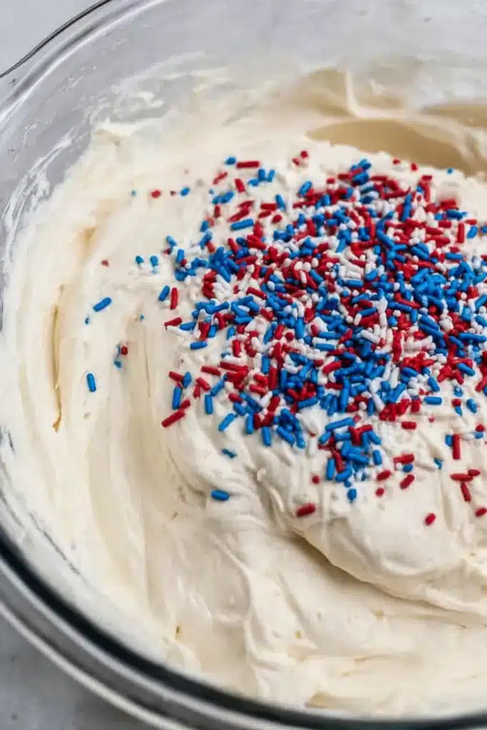 Red White and Blue Funfetti Dip 3 Red White and Blue Funfetti Dip with patriotic sprinkles in mixing bowl