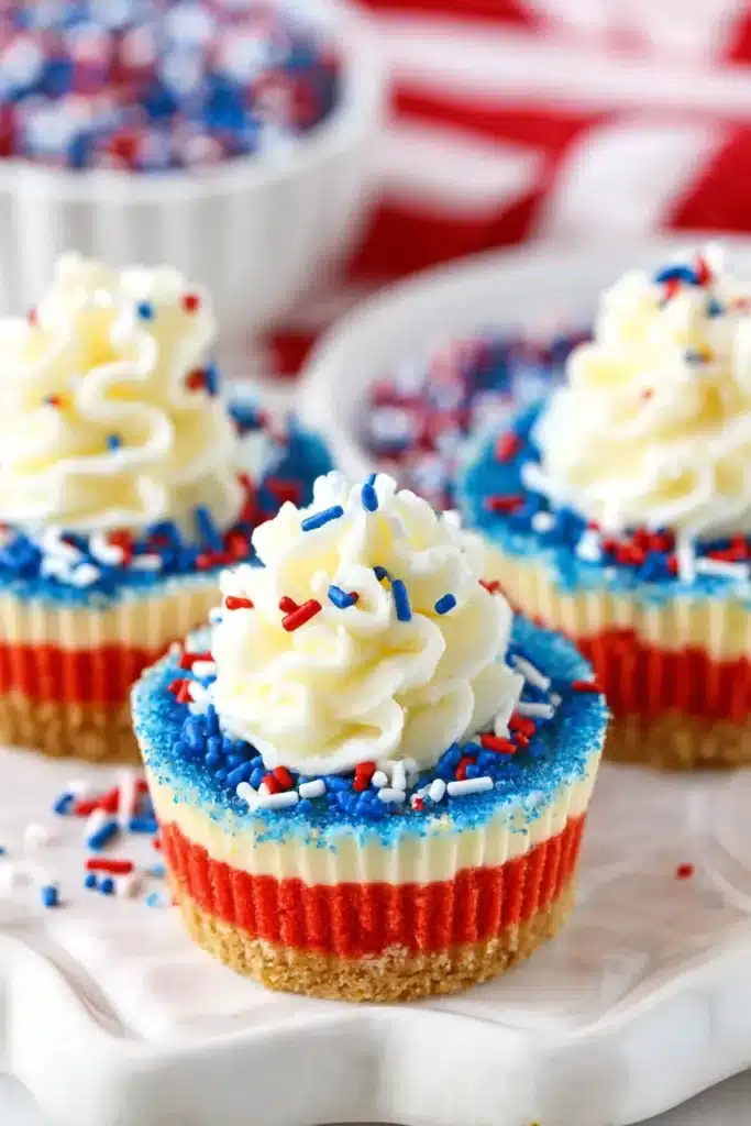 Red White and Blue Mini Cheesecakes with whipped cream and patriotic sprinkles