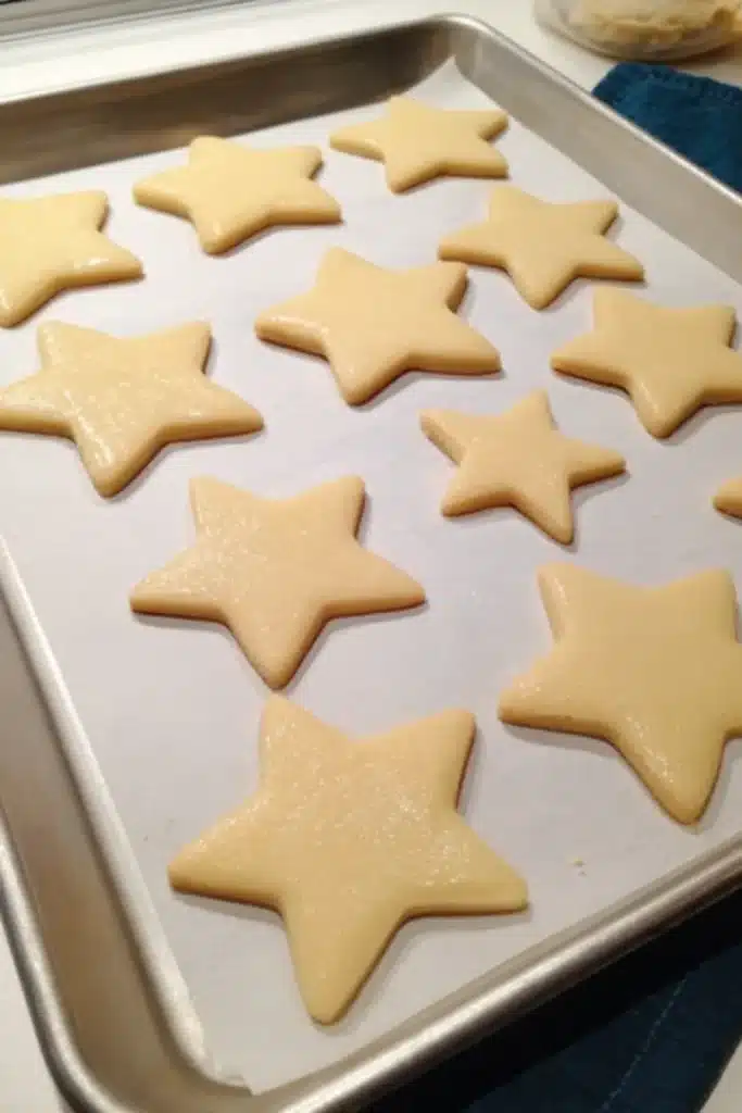 Star Cookies with light blue royal icing on a parchment lined baking sheet