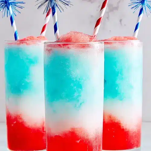 Three Frozen Bomb Pop Cocktails with red white and blue frozen layers in tall glasses