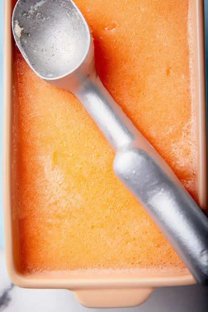 Peach Sorbet 4 Peach Sorbet frozen in a container with a scoop ready to serve