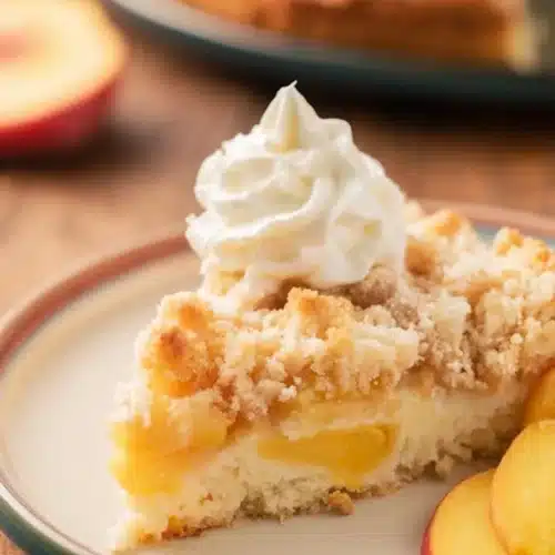 Easy Italian Peach Crumb Cake 3 Easy Italian peach crumb cake slice with whipped cream and fresh peach slices on a plate